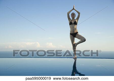 Woman standing in tree pose on edge of infinity pool View Large Photo Image Stock Photo - Woman standing in tree pose on edge of infinity pool. Fotosearch