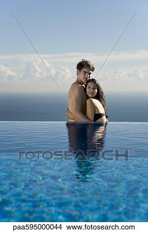 Young couple embracing at edge of infinity pool View Large Photo Image Picture - Young couple embracing at edge of infinity pool. Fotosearch