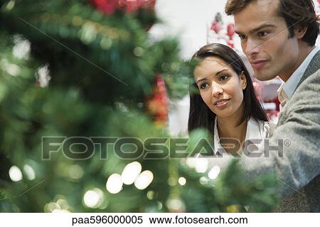 Stock Photography - Couple decorating Christmas tree together. Fotosearch