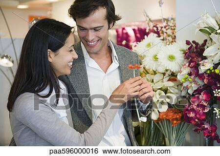 Couple looking at artificial flowers together View Large Photo Image Stock Photograph - Couple looking at artificial flowers together. Fotosearch