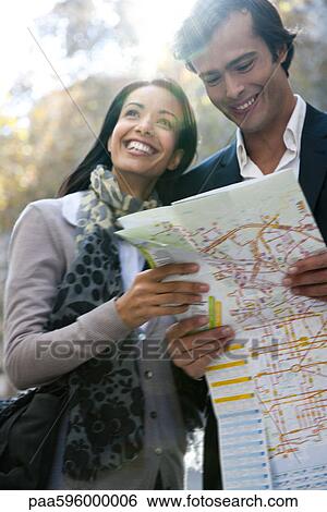 Stock Photograph - Couple sightseeing together, consulting map. Fotosearch