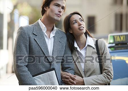 Couple standing outdoors, looking up in interest View Large Photo Image Stock Image - Couple standing outdoors, looking up in interest. Fotosearch