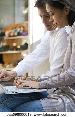 Stock Photo - Couple using laptop computer together in cafe. Fotosearch