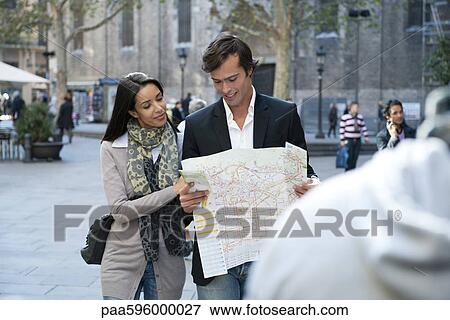 Stock Photo - Couple walking outdoors, consulting map. Fotosearch
