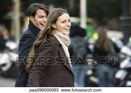 Stock Image - Young couple laughing and walking together outdoors. Fotosearch
