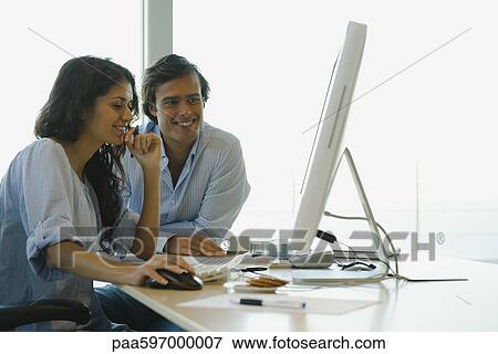 Couple looking at desktop computer together, both smiling View Large Photo Image Stock Photo - Couple looking at desktop computer together, both smiling. Fotosearch