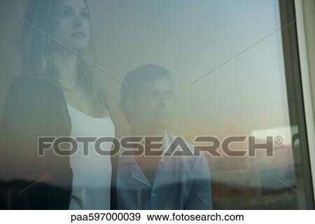 Couple looking through window View Large Photo Image Stock Photo - Couple looking through window. Fotosearch