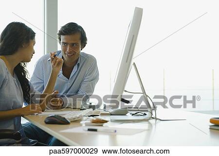 Couple sitting together at computer desk View Large Photo Image Stock Photo - Couple sitting together at computer desk. Fotosearch