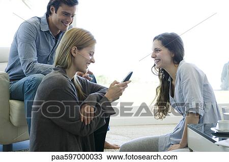 Stock Image - Friends hanging out in living room. Fotosearch