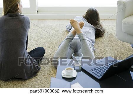 Friends hanging out together in living room View Large Photo Image Stock Image - Friends hanging out together in living room. Fotosearch