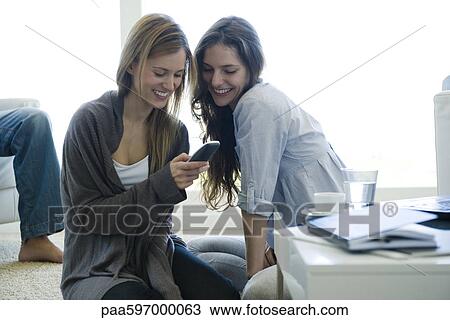 Friends hanging out together in living room, looking at cell phone View Large Photo Image Stock Image - Friends hanging out together in living room, looking at cell phone. Fotosearch