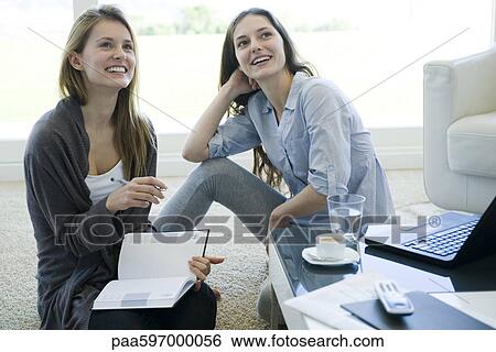 Stock Photograph - Friends hanging out together in living room. Fotosearch