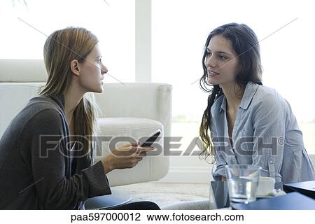 Stock Image - Friends talking together in living room. Fotosearch