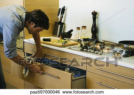 Man cooking in kitchen, looking in drawer View Large Photo Image Stock Photograph - Man cooking in kitchen, looking in drawer. Fotosearch