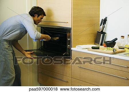 Man putting pan into oven View Large Photo Image Stock Photo - Man putting pan into oven. Fotosearch