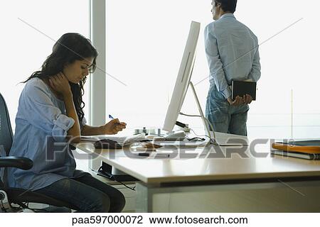 Woman working at desk at home, husband looking out window in background View Large Photo Image Stock Image - Woman working at desk at home, husband looking out window in background. Fotosearch