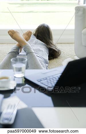 Young woman lying on stomach on floor, looking out window View Large Photo Image Stock Photo - Young woman lying on stomach on floor, looking out window. Fotosearch