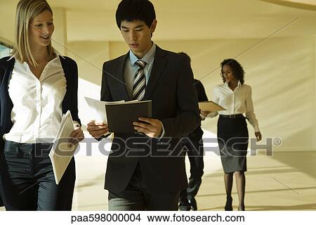 Picture - Business associates walking and discussing documents. Fotosearch