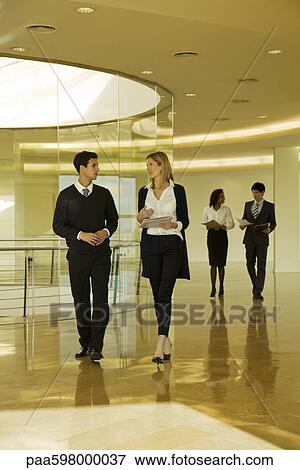 Business associates walking and discussing documents View Large Photo Image Stock Photo - Business associates walking and discussing documents. Fotosearch