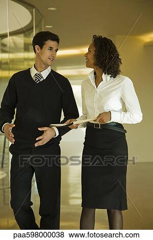 Business associates walking and discussing documents View Large Photo Image Stock Photo - Business associates walking and discussing documents. Fotosearch