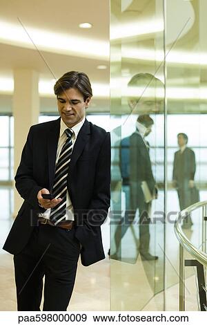 Businessman text messaging in lobby View Large Photo Image Stock Photo - Businessman text messaging in lobby. Fotosearch
