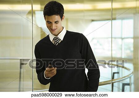 Stock Photo - Businessman text messaging with cell phone. Fotosearch