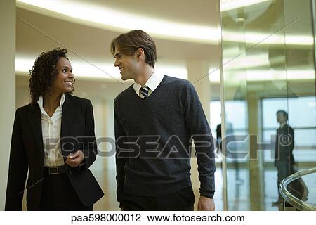 Executives talking as they walk together in corridor View Large Photo Image Stock Image - Executives talking as they walk together in corridor. Fotosearch