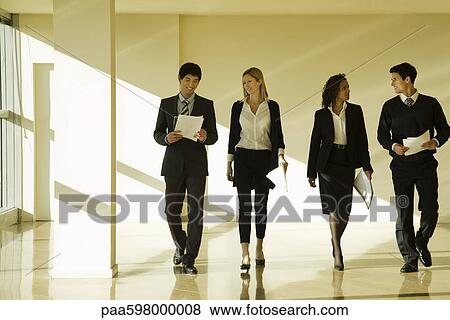 Group of business associates talking as they walk together in lobby View Large Photo Image Stock Photo - Group of business associates talking as they walk together in lobby. Fotosearch