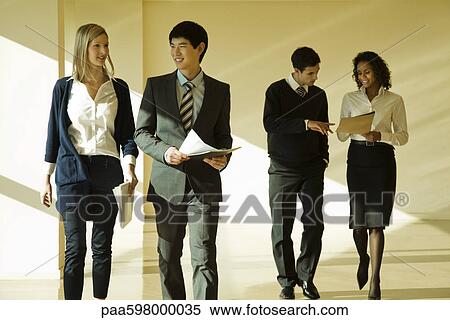 Group of business associates talking as they walk together in lobby View Large Photo Image Stock Photography - Group of business associates talking as they walk together in lobby. Fotosearch