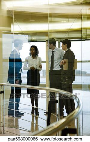 Stock Photograph - Group of executives talking in corridor. Fotosearch