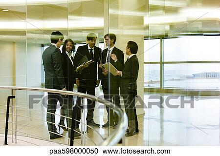 Stock Image - Team of executives meeting in corridor. Fotosearch