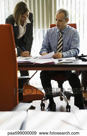 Businessman talking to female colleague as she making notes View Large Photo Image Stock Photo - Businessman talking to female colleague as she making notes. Fotosearch