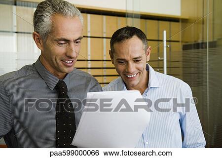 Businessmen looking at document together View Large Photo Image Stock Photograph - Businessmen looking at document together. Fotosearch