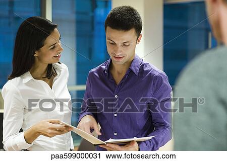Colleagues discussing work together in office View Large Photo Image Stock Image - Colleagues discussing work together in office. Fotosearch
