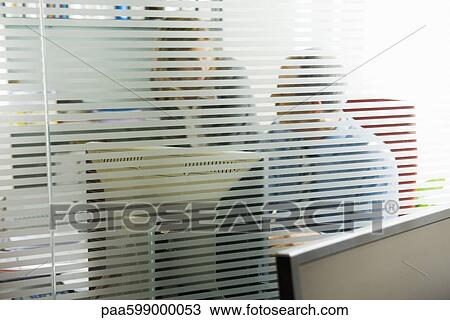 Colleagues having private conversation in office View Large Photo Image Stock Image - Colleagues having private conversation in office. Fotosearch