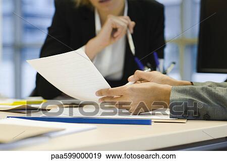 Stock Photo - Executives discussing document, cropped. Fotosearch