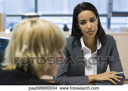 Female executive listening to colleague talk View Large Photo Image Picture - Female executive listening to colleague talk. Fotosearch