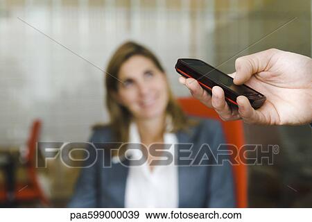 Stock Photo - Person using cell phone, female executive in background. Fotosearch