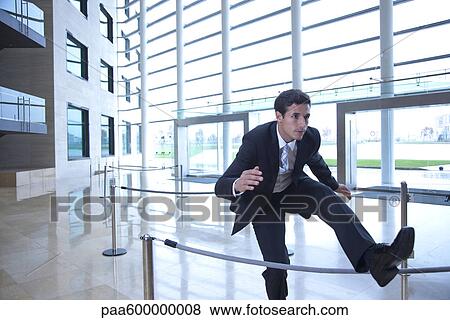 Stock Photo - Businessman jumping over rope in lobby. Fotosearch