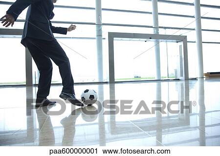 Businessman kicking soccer ball in lobby View Large Photo Image Stock Image - Businessman kicking soccer ball in lobby. Fotosearch
