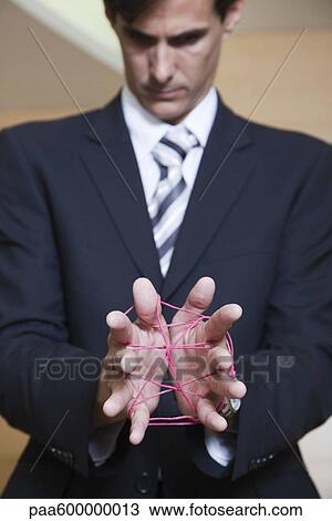 Stock Image - Businessman playing cat's cradle with string. Fotosearch