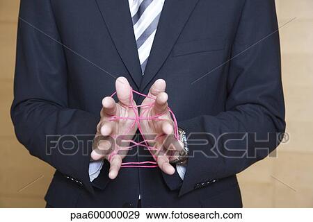 Stock Photo - Businessman playing cat's cradle with string. Fotosearch