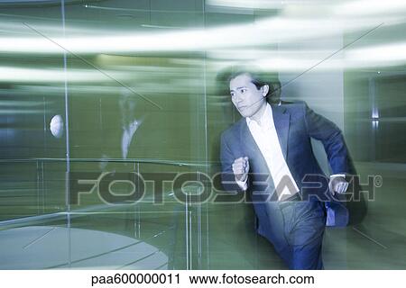 Stock Image - Businessman running in lobby. Fotosearch