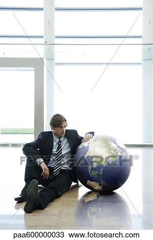 Businessman sitting next to ball in lobby View Large Photo Image Stock Image - Businessman sitting next to ball in lobby. Fotosearch