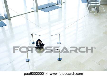 Businessman sitting on floor inside roped off area in lobby View Large Photo Image Picture - Businessman sitting on floor inside roped off area in lobby. Fotosearch