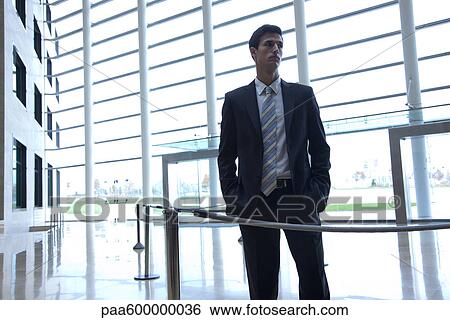 Stock Photograph - Businessman standing in lobby. Fotosearch