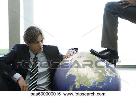 Businessman stepping on ball while colleague watches View Large Photo Image Stock Photograph - Businessman stepping on ball while colleague watches. Fotosearch