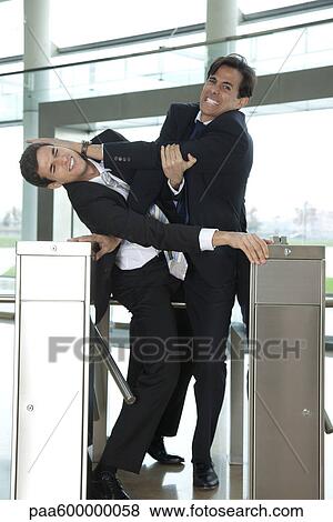 Stock Photo - Businessmen fighting to beat each other through turnstile. Fotosearch