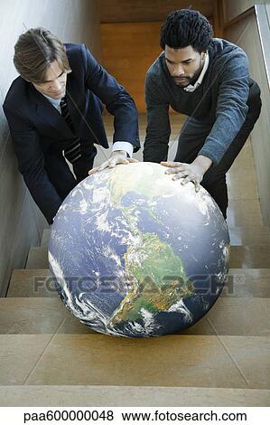 Businessmen pushing ball up stairs together View Large Photo Image Stock Photo - Businessmen pushing ball up stairs together. Fotosearch