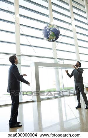 Picture - Businessmen throwing ball in lobby. Fotosearch